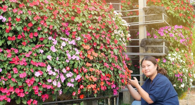 La mujer asiática se siente feliz con la flor en su jardín