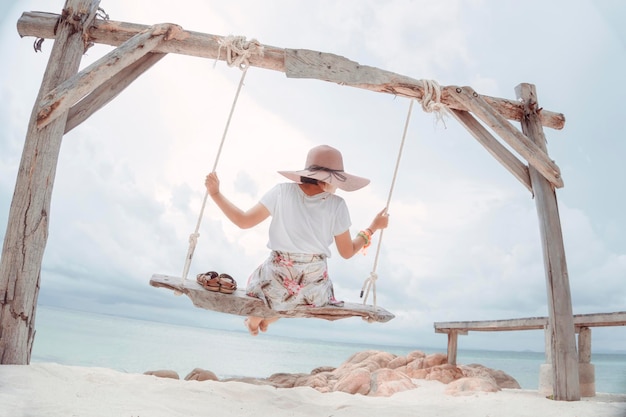 Mujer asiática Siéntese en la hamaca de la playa Refresco y disfrute con el concepto de naturaleza