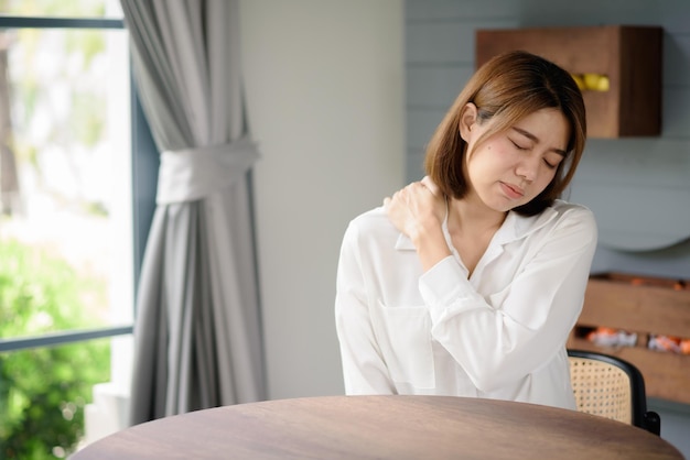 Una mujer asiática con síntomas de dolor en el hombro.