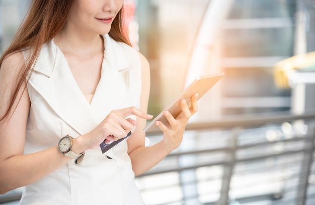 Mujer asiática con sitio web en línea de compras de smartphone en smartphone con cara sonriente