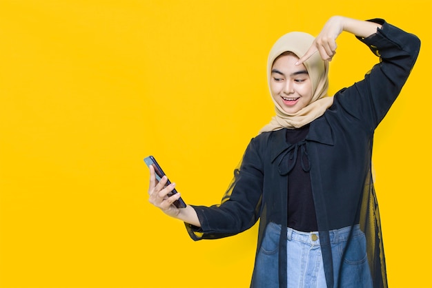 Mujer asiática con smartphone en pared amarilla