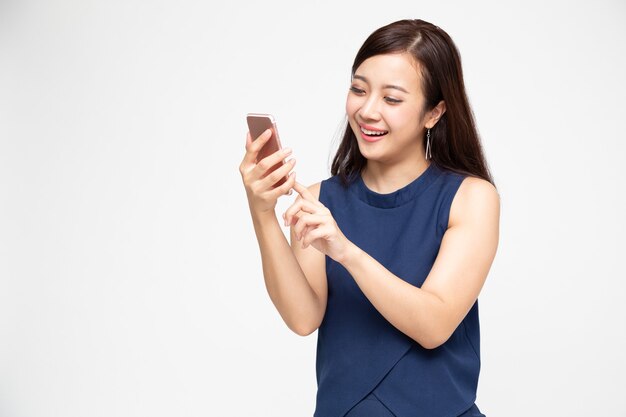 Mujer asiática con smartphone en pared blanca