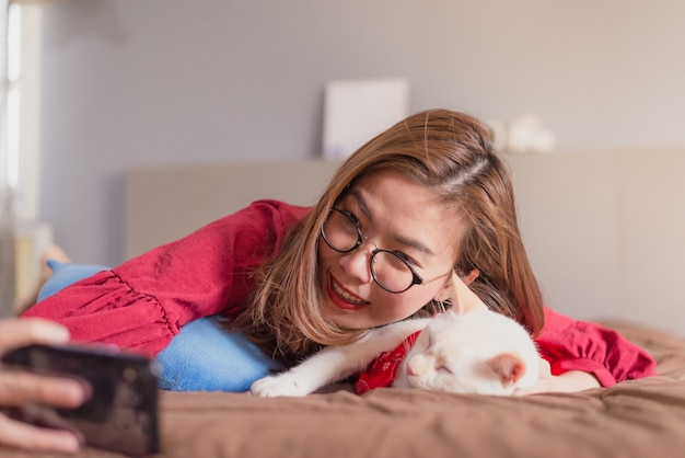 Mujer asiática con smartphone para selfie en cama