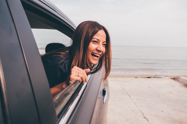 Mujer asiática smilng con el espejo en el coche.