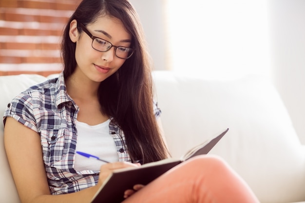 Mujer asiática en el sofá escribiendo