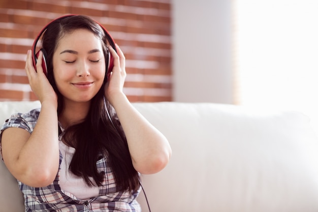 Mujer asiática en el sofá escuchando música