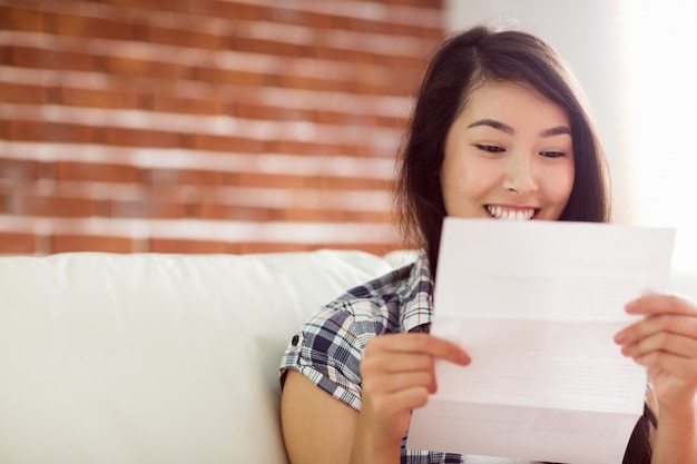 Mujer asiática en el sofá leyendo carta