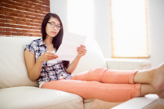 Mujer asiática en el sofá leyendo carta