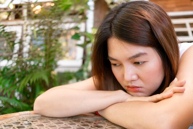 Una mujer asiática solitaria y aburrida esperando a su amiga sola en la cafetería.