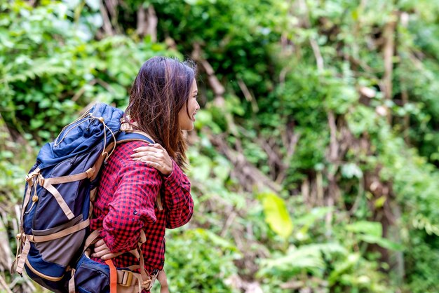 Mujer asiática con sombrero y mochila sintiendo dolor de espalda