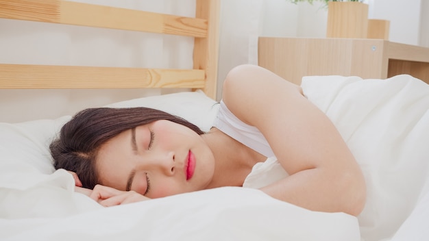 Foto mujer asiática soñando mientras duerme en la cama en el dormitorio