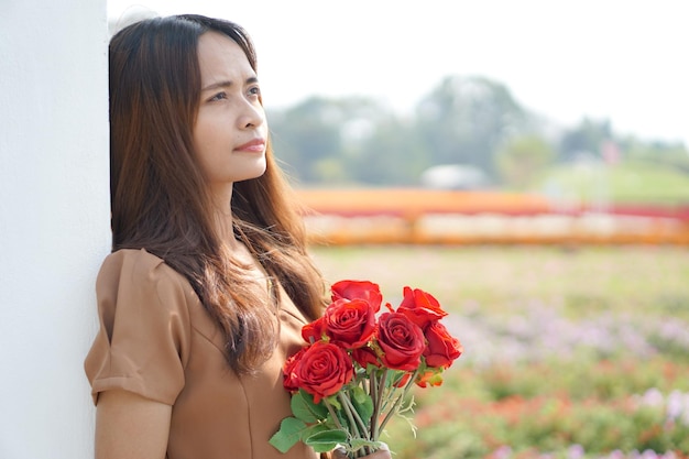 Mujer asiática sonriendo felizmente entre hermosas flores