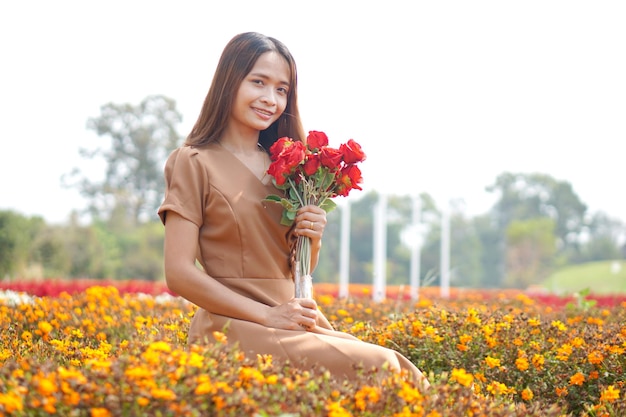 Mujer asiática sonriendo felizmente entre hermosas flores