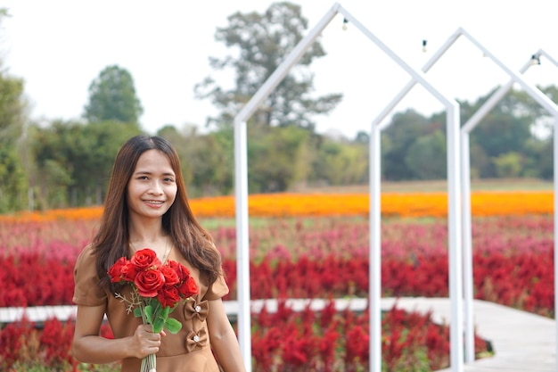 Mujer asiática sonriendo felizmente entre hermosas flores