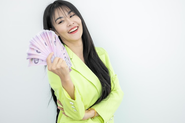 Mujer asiática sonriendo mientras sostiene el dinero del baht de Tailandia en las manos sobre fondo blanco Mujer asiática celebra la felicidad riqueza dinero feliz cara sonriente Mujer asiática con billetes en efectivo