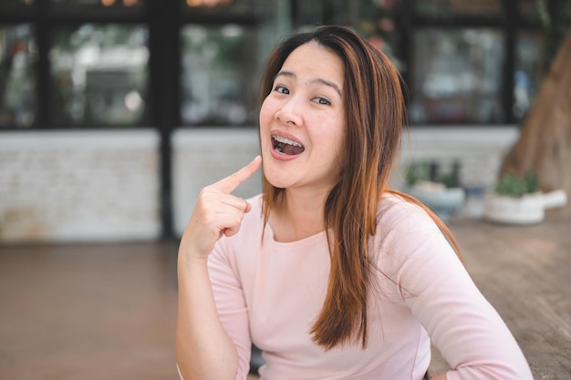 Mujer asiática sonriente con retenedor de ortodoncia. Cuidado dental y dientes sanos.