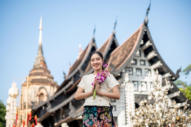 Una mujer asiática sonriente en un vestido tradicional con un hermoso templo y una pagoda en el fondo