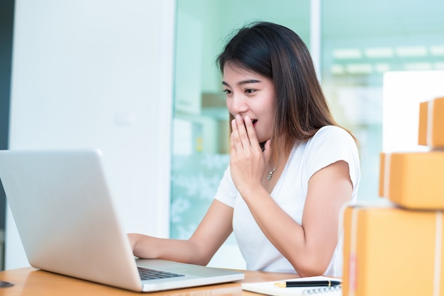 Mujer asiática sorprendente al usar la computadora portátil para ir de compras o de marketing en línea