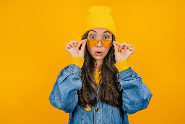 Mujer asiática sorprendida con sombrero amarillo y gafas de sol que buscan emoción