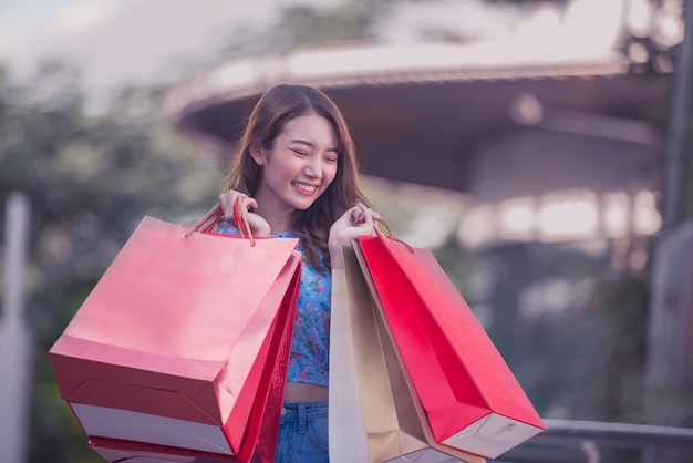 Mujer asiática sosteniendo bolsas de compras y levantó las manos