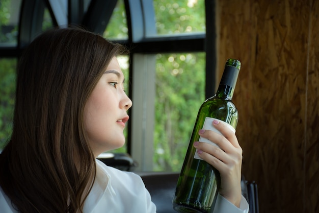 Mujer asiática sosteniendo una botella de vino / Mujer seleccionando una botella de vino en el restaurante