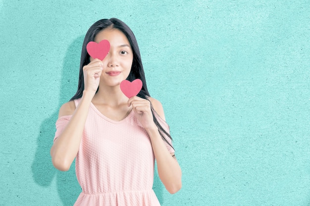 Mujer asiática sosteniendo el corazón rojo con un fondo de color. Día de San Valentín