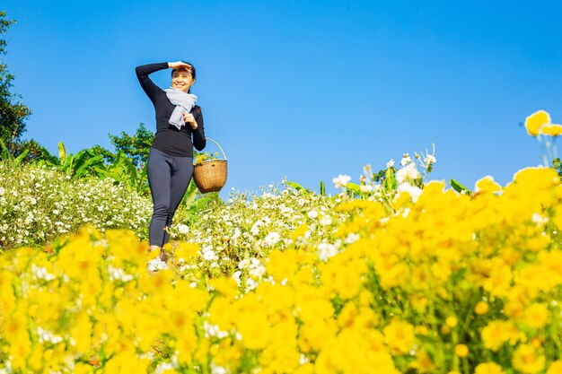 Mujer asiática sosteniendo la flor de los crisantemos y mirando hacia adelante en el jardín floral