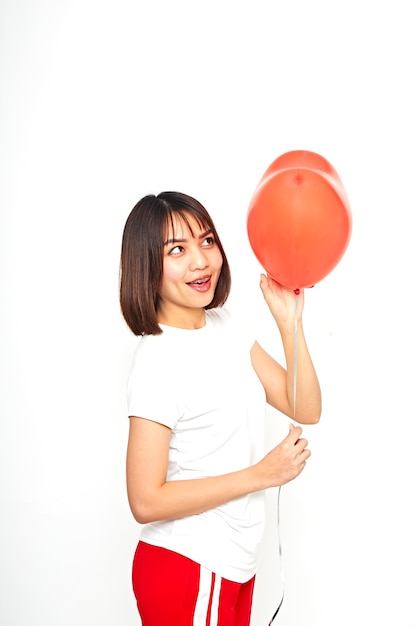 Mujer asiática sosteniendo un globo corazón rojo
