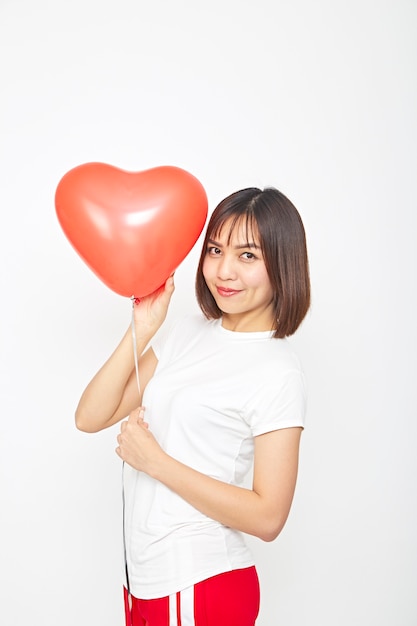 Mujer asiática sosteniendo un globo corazón rojo