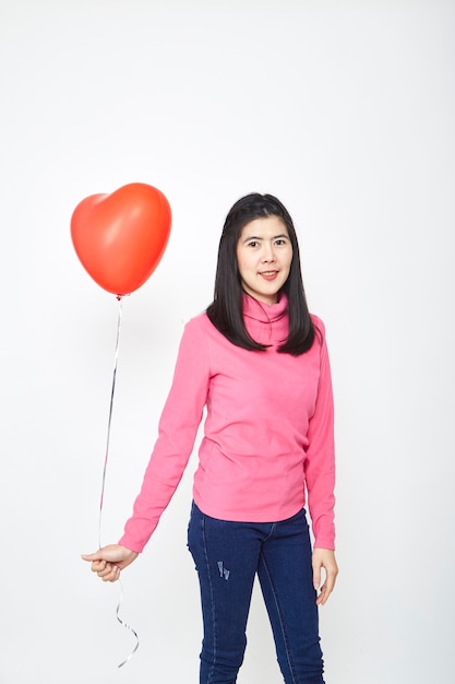 Mujer asiática sosteniendo un globo corazón rojo