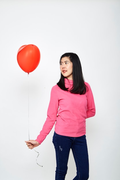 Mujer asiática sosteniendo un globo corazón rojo