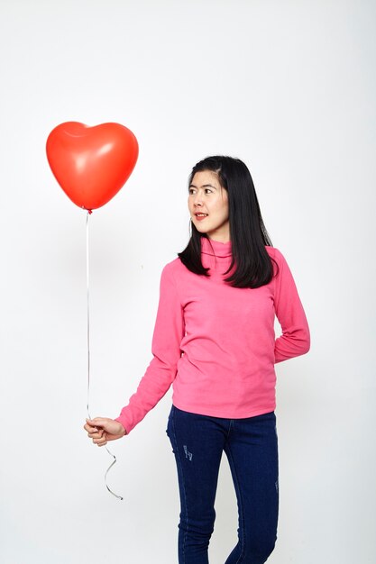 Mujer asiática sosteniendo un globo corazón rojo