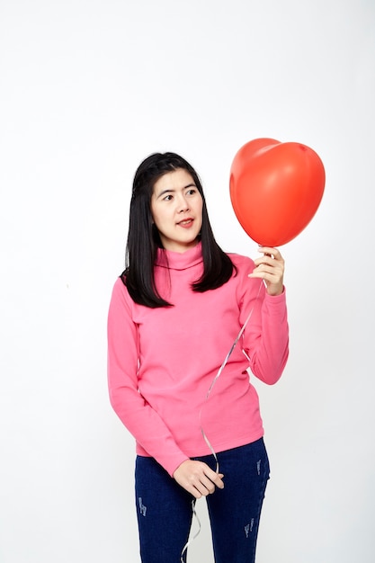 Mujer asiática sosteniendo un globo corazón rojo