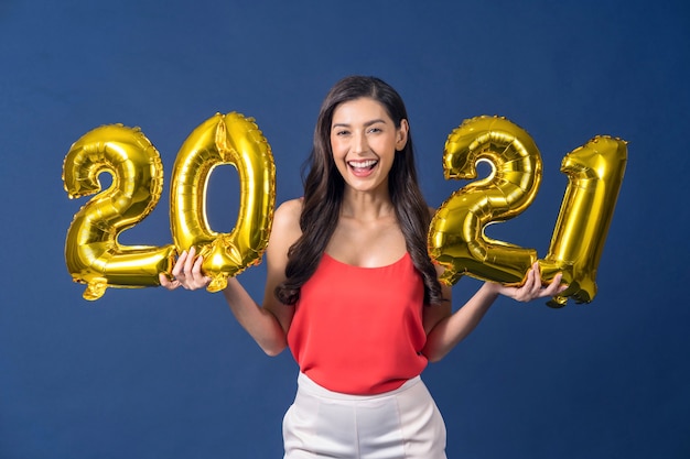 Mujer asiática sosteniendo globos de color dorado para celebrar feliz Navidad y próspero año nuevo