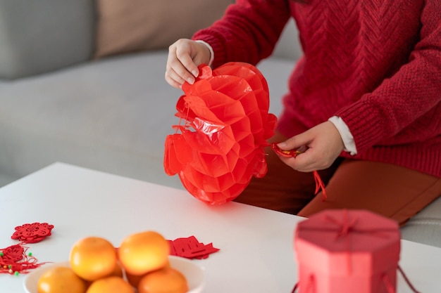 Mujer asiática sosteniendo una linterna china roja del año nuevo mientras está decorada con un colgante tradicional en las celebraciones del Año Nuevo chino para la buena suerte, la palabra china significa bendición