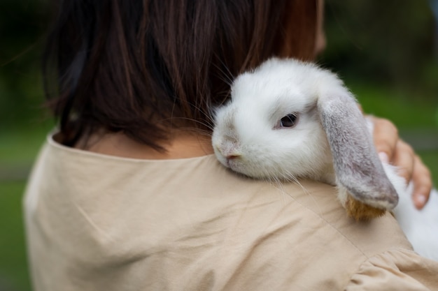 Foto mujer asiática sosteniendo y llevando lindo conejo con ternura y amor. amistad con lindo conejito de pascua. conejo feliz con dueño.