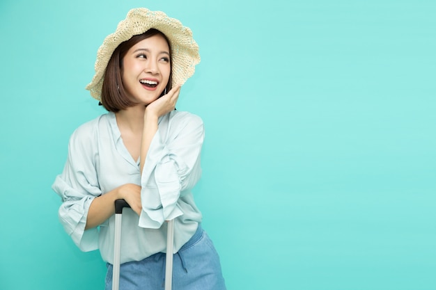 Mujer asiática sosteniendo la maleta y sonriendo aislado