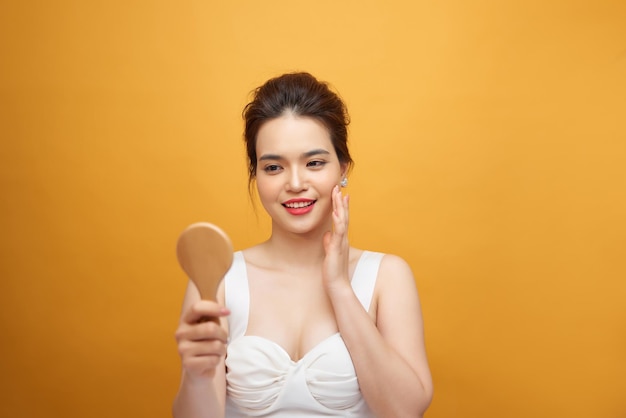 Mujer asiática sosteniendo y mirando en un espejo de madera clásico.