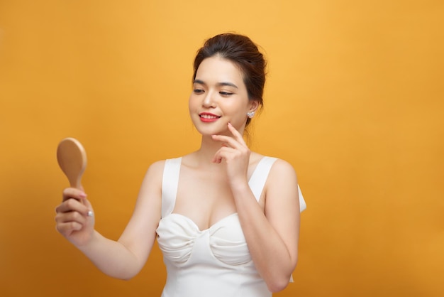 Mujer asiática sosteniendo y mirando en un espejo de madera clásico