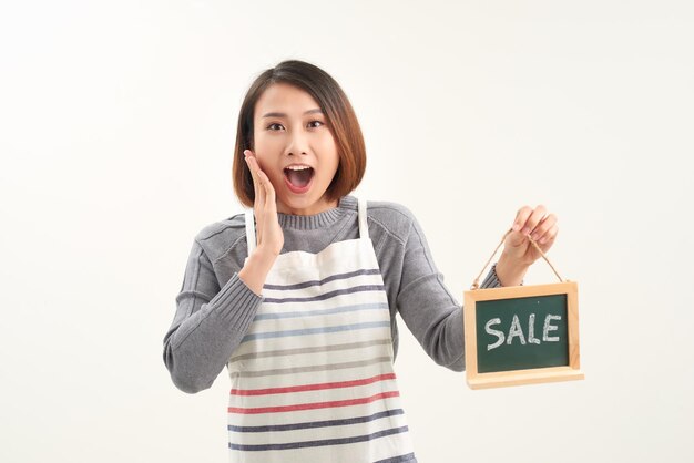 Foto mujer asiática sosteniendo un tablero de venta sobre un fondo blanco aislado muy feliz y emocionada con una gran sonrisa y las manos levantadas