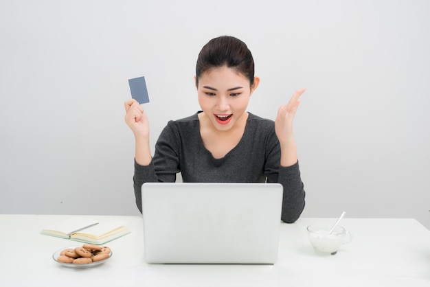 Mujer asiática sosteniendo una tarjeta de crédito y comprando en línea