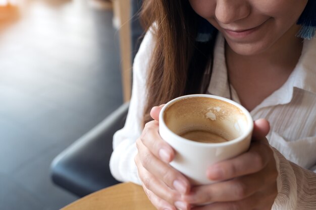 una mujer asiática sosteniendo una taza de café y bebiendo