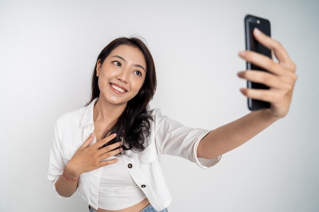 Mujer asiática sosteniendo un teléfono inteligente para selfie o videollamada