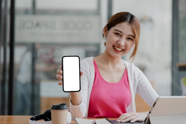 Mujer asiática sosteniendo un teléfono de pantalla en blanco blanco de pie delante de la pantalla en blanco del teléfono inteligente para la aplicación de teléfono inteligente de publicidad Ideas de collage de fotos para espacio de copia de anuncios