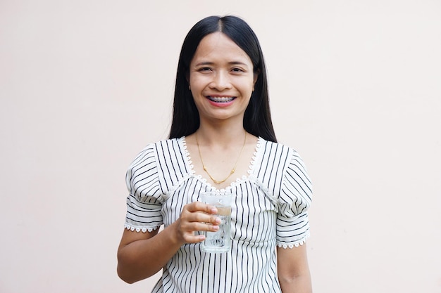 Mujer asiática sosteniendo un vaso de agua fría para beber