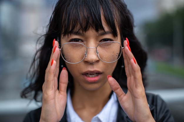 Mujer asiática sostiene sus gafas con las manos