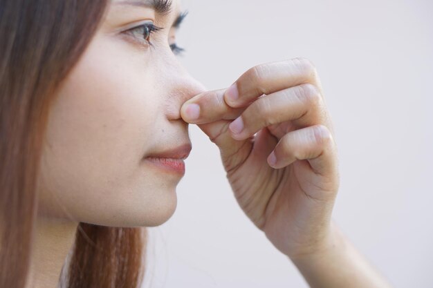 Mujer asiática tapándose la nariz con las manos debido a un mal olor
