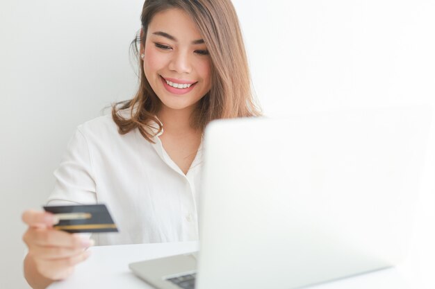 Mujer asiática con tarjeta de crédito de compras en línea con computadora portátil
