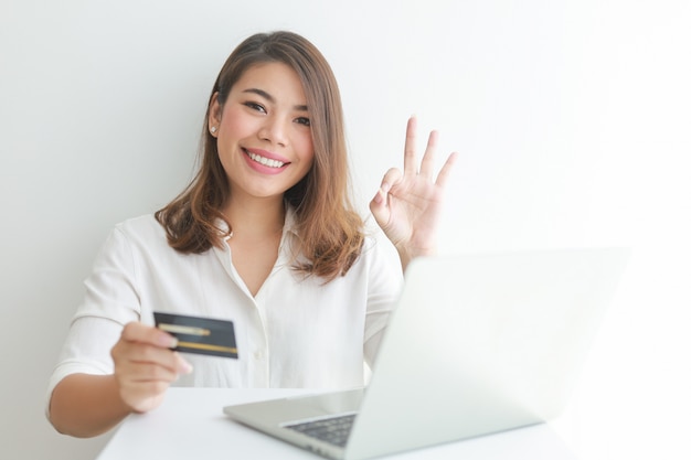 Mujer asiática con tarjeta de crédito de compras en línea con computadora portátil