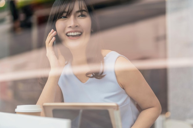 Mujer asiática con tarjeta de crédito con teléfono móvil para compras en línea en cafetería moderna,